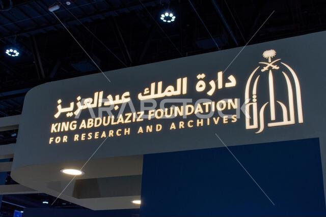 لافتة مضيئة تحمل شعار ونص ثنائي اللغة لمؤسسة الملك عبد العزيز للبحوث والمحفوظات معروضة في أحد المعارض.