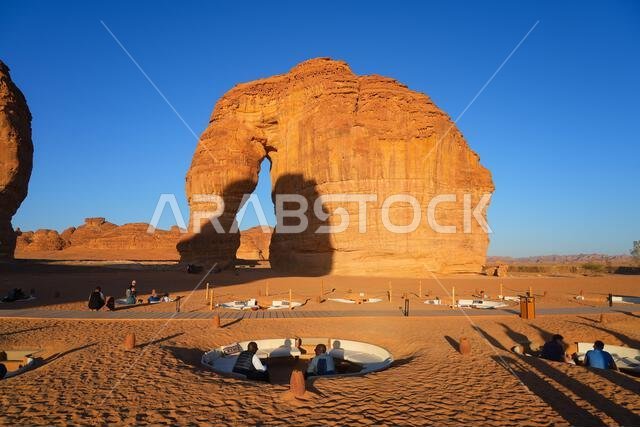 صالة صحراوية فاخرة عند سفح جبل الفيل (صخرة الفيل) عند غروب الشمس في صحراء العلا، المملكة العربية السعودية