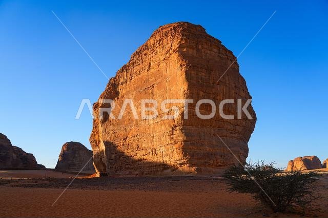 تكوين صخري من الحجر الرملي بجوار صخرة الفيل (جبل الفيل) عند غروب الشمس في صحراء العلا، المملكة العربية السعودية