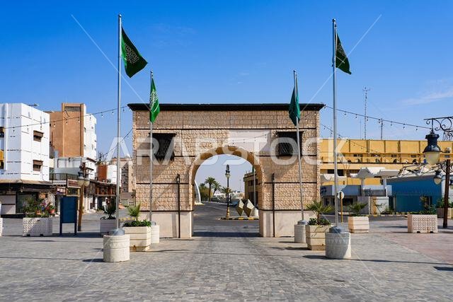 المدخل الحجري لحي ينبع التاريخي مزين بالأعلام السعودية