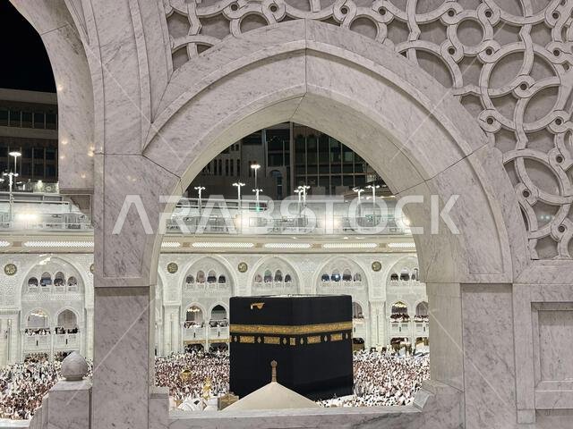Pilgrims circling the Kaaba at Masjid al-Haram in Mecca seen through ornate marble arch