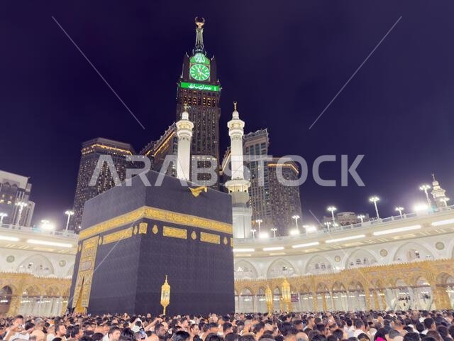 الحجاج يؤدون طواف الكعبة المشرفة في المسجد الحرام بمكة المكرمة، مع برج ساعة أبراج البيت ليلاً.