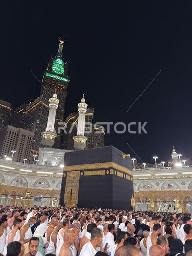 Pilgrims praying around the Kaaba at Masjid al Haram with Abraj Al Bait clock tower at night