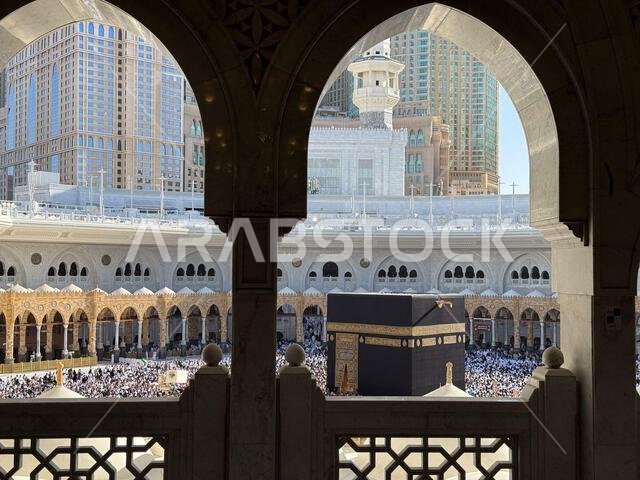 الحجاج يطوفون حول الكعبة المشرفة في المسجد الحرام بمكة المكرمة، محاطين بأقواس المسجد المزخرفة خلال موسم الحج.