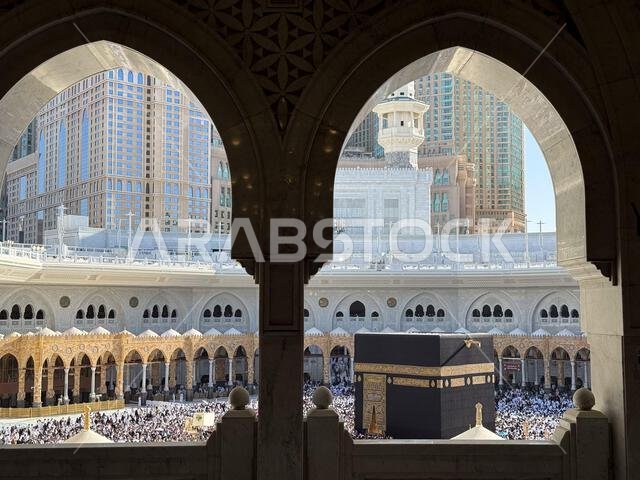 Pilgrims circling the Kaaba at Masjid al-Haram in Mecca with crowds framed by mosque arches