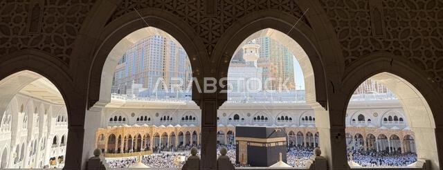 الحجاج يؤدون طوافهم حول الكعبة المشرفة كما يُرى من خلال أقواس المسجد الحرام المزخرفة في مكة المكرمة
