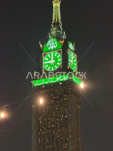 برج ساعة مكة ليلاً مع وجه ساعة أخضر مضاء على برج البيت
