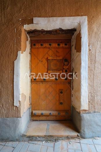 Restored traditional Najdi wooden door with iron decorative studs in Shaqra, Saudi Arabia