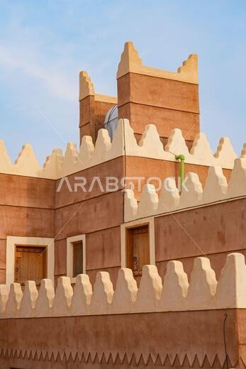 Traditional Najdi mud brick house with white crenelations in Shaqra, a historical desert village in the Washm region of Saudi Arabia