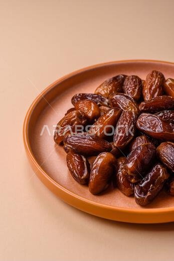 Dried dates on a ceramic plate for Ramadan or Iftar. Dried dates as a food background for your design