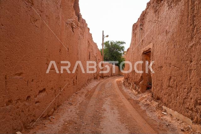 Narrow sandy alleyway between ancient mud brick walls in historic Shaqra, Saudi Arabia