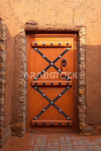 Restored traditional Najdi wooden door with iron decorative studs in Shaqra, Saudi Arabia