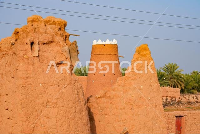Traditional Najdi mud brick watchtower with white crenelations in Shaqra, a historical desert village in Saudi Arabia