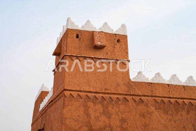 Traditional Najdi mud brick fortification with white crenelations in Shaqra, Saudi Arabia