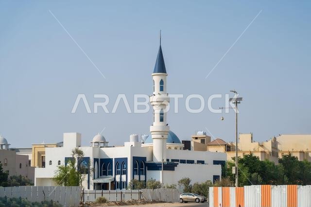 مئذنة المسجد، مئذنة رشيقة تخترق سماء الغسق. مبنى سوق عربي تقليدي ذو جدران مسننة يقف شامخًا على سفح تل صخري.