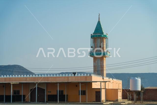 مئذنة المسجد، مئذنة رشيقة تخترق سماء الغسق. مبنى سوق عربي تقليدي ذو جدران مسننة يقف شامخًا على سفح تل صخري.