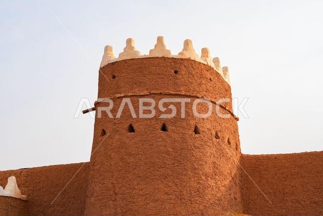 Traditional Najdi mud brick watchtower with white crenelations in Shaqra, a historical desert village in Saudi Arabia