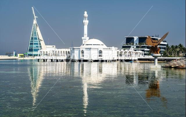 Jeddah, Saudi Arabia - February 11, 2026: The Al Rahmah Mosque, modern Jeddah Yacht Club building and the Golden Eagle Statue reflected in the waters of the Red Sea along the city corniche. Jeddah, Saudi Arabia - February 11, 2026: The Al Rahmah Mosque, modern Jeddah Yacht Club building and the Golden Eagle Statue reflected in the waters of the Red Sea along the city corniche.