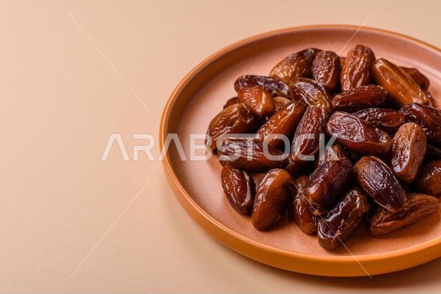 Dried dates on a ceramic plate for Ramadan or Iftar. Dried dates as a food background for your design