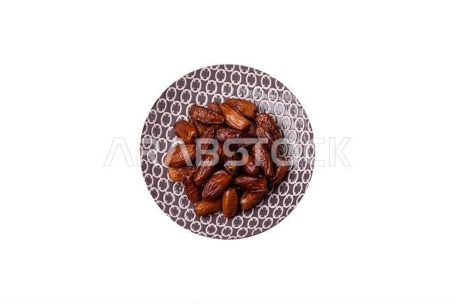 Dried dates on a ceramic plate for Ramadan or Iftar. Dried dates as a food background for your design