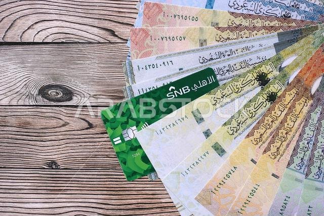 كييف، أوكرانيا - ٢٨ يناير ٢٠٢٦: صورة مقرّبة لبطاقة البنك الوطني السعودي وأوراق نقدية من الريال السعودي على طاولة. يُعدّ البنك الوطني السعودي البنك الأكثر شعبية في المملكة العربية السعودية. كييف، أوكرانيا - ٢٨ يناير ٢٠٢٦: صورة مقرّبة لبطاقة البنك الوطني السعودي وأوراق نقدية من الريال السعودي على طاولة. يُعدّ البنك الوطني السعودي البنك الأكثر شعبية في المملكة العربية السعودية.
