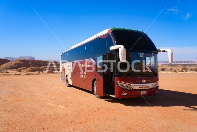 Modern Hop-On Hop-Off tourist bus in the desert surrounding Hegra in AlUla, Saudi Arabia