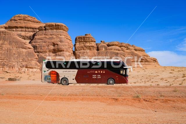حافلة سياحية حديثة بنظام الصعود والنزول في الصحراء المحيطة بالحِجر في العلا، المملكة العربية السعودية