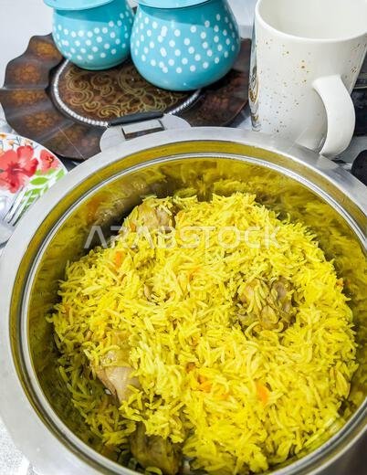 منظر علوي لطبق دجاج مطبوخ منزلياً في السعودية مع أرز متبل يقدم في مقلاة على طاولة الطعام.