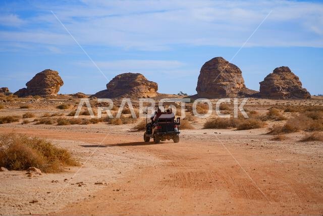Tourists exploring the ancient site of Hegra in an electric vehicle, AlUla, Saudi Arabia