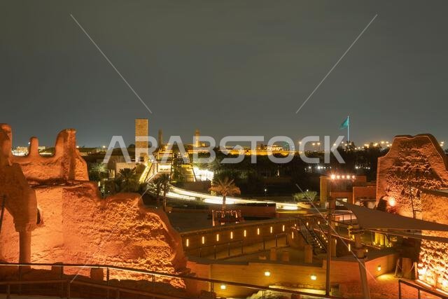 Diriyah at-turaif complex showing mud-brick architecture and palm trees glowing under night lights, Riyadh, Saudi Arabia