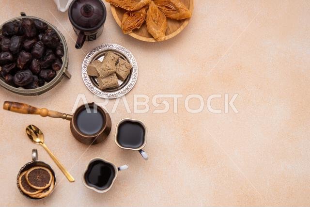 حلويات شرقية وأكواب قهوة على الطاولة خلال شهر رمضان. بقلاوة وتمر من الأعلى. خلفية من الحلويات مع مساحة للكتابة.