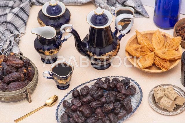 طقم قهوة يتضمن إبريقًا، وإبريقًا للكريمة، وأكوابًا. أدوات مائدة عتيقة. حلويات شرقية وقهوة على الطاولة. بقلاوة، وحلوى حلاوة طحينية، وتمر للتحلية. مأكولات ومشروبات.