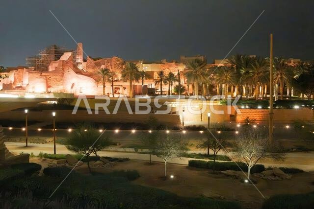 Diriyah at-turaif complex showing mud-brick architecture and palm trees glowing under night lights, Riyadh, Saudi Arabia