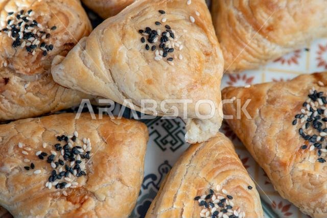 سمسا مصنوعة من عجينة الباف باستري. فطيرة مثلثة الشكل محشوة باللحم ومغطاة ببذور السمسم (من الأعلى). طعام آسيوي مخبوز.