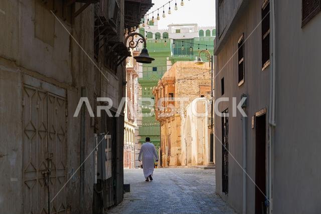 Traditional Saudi man walking through the historic Al-Balad district, the Old Town of Jeddah, Saudi Arabia