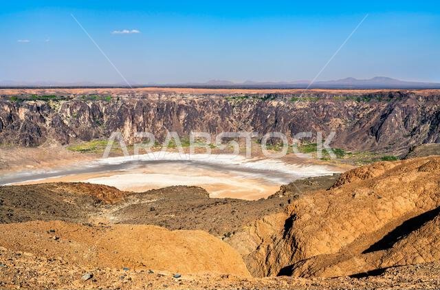 منظر بانورامي بزاوية عالية يظهر القشرة الملحية البيضاء والجدران شديدة الانحدار لفوهة بركان الوهبة الواقعة في صحراء المملكة العربية السعودية.