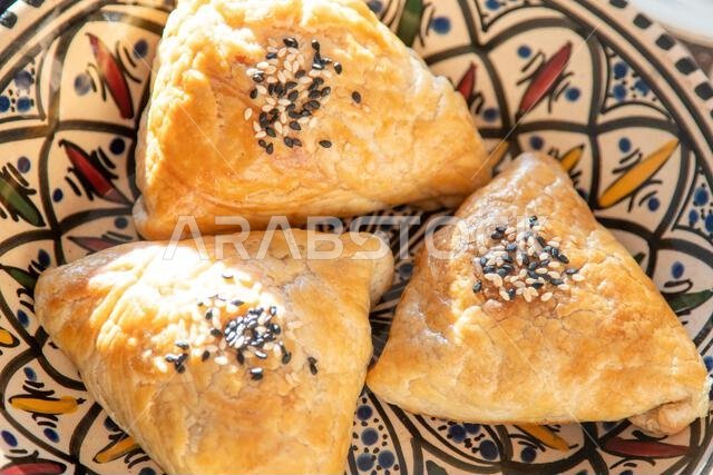 Uzbek food. Samosa made from puff pastry dough. A triangular pie with meat filling, sprinkled with sesame seeds. Plate top view