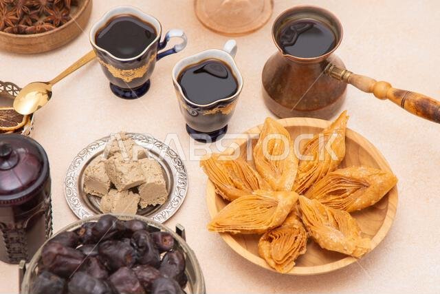 تشكيلة من الحلويات الرمضانية والقهوة على الطاولة. بقلاوة وحلوى حلاوة طحينية للتحلية. مأكولات ومشروبات. تمر.