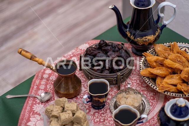 Oriental sweets and coffee cezve on the table. Baklava, halva, Dates fruit for dessert. Food and drink.