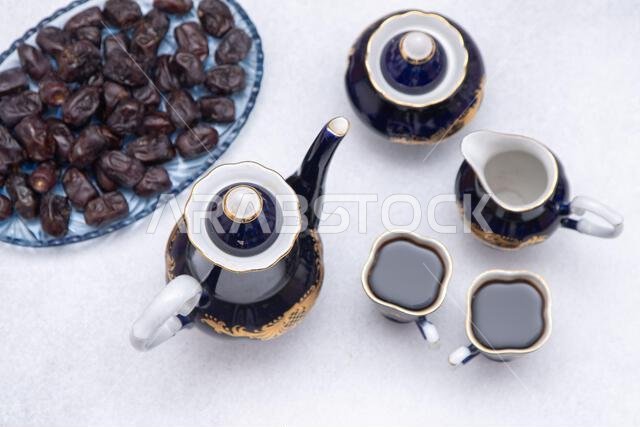 Coffee set with decanter, creamer, blue sugar bowl and two cups . Vintage tableware. Sweet dates fruit top view table.