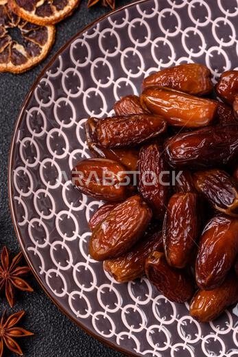 Dried dates on a ceramic plate for Ramadan or Iftar. Dried dates as a food background for your design