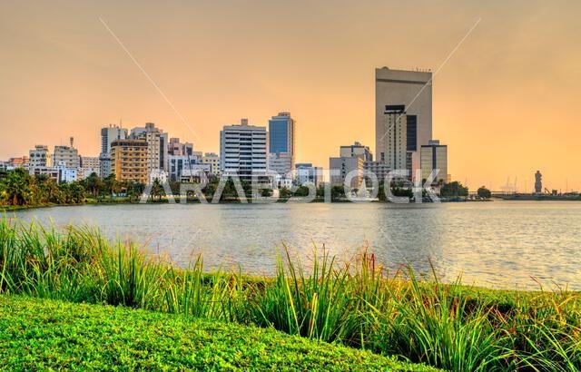 A view of the modern Jeddah city skyline across Lake Arbaeen in Saudi Arabia during sunset.