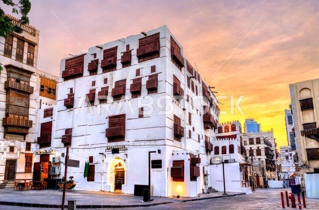 منظر للمباني التاريخية ذات النوافذ الخشبية التقليدية (المشربية) في حي البلد بجدة، المملكة العربية السعودية، عند غروب الشمس.