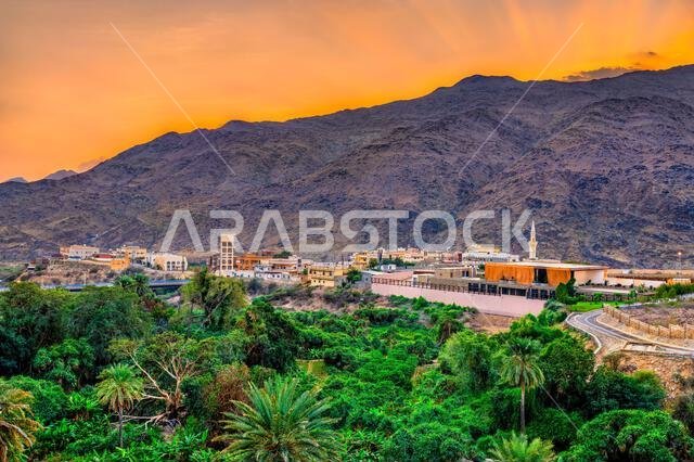 غروب شمس جميل فوق الجبال وبساتين النخيل الخضراء المحيطة بقرية ذي عين في منطقة الباحة بالمملكة العربية السعودية.