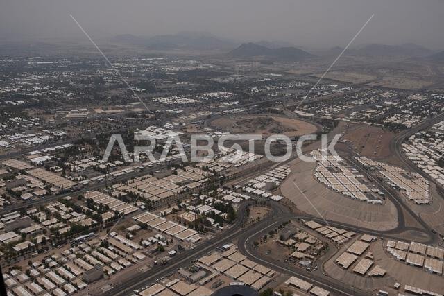 منظر جوي لمنطقة حضرية مترامية الأطراف تضم العديد من المباني السكنية والطرق والمساحات المفتوحة تحت سماء ضبابية. منظر جوي لمنطقة حضرية مترامية الأطراف تضم العديد من المباني السكنية والطرق والمساحات المفتوحة تحت سماء ضبابية.