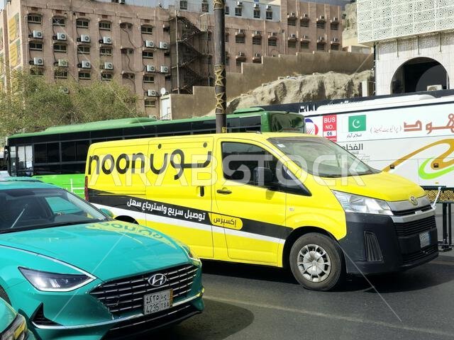 Mecca, Saudi Arabia, June 11 2024: Noon online shopping delivery yellow van to deliver a package, Arabic Translation (Noon.com express for fast delive Mecca, Saudi Arabia, June 11 2024: Noon online shopping delivery yellow van to deliver a package, Arabic Translation (Noon.com express for fast delive