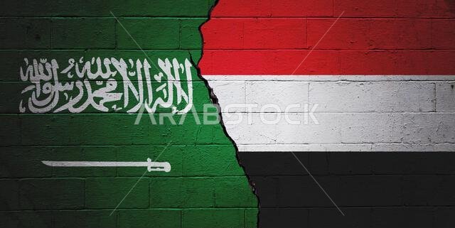 جدار من الطوب الخرساني المتشقق مطلي بعلم المملكة العربية السعودية على اليسار وعلم اليمن على اليمين.
