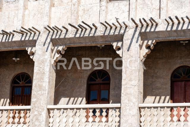 Traditional Arabian building with balconies and intricate details. The building is made of whitewashed stone and has a series of arched windows