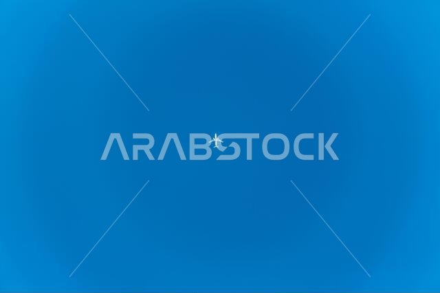 رحلة طيران بسيطة: طائرة ركاب تحلق عبر السماء الزرقاء الشاسعة فوق مدينة الخبر، المملكة العربية السعودية.