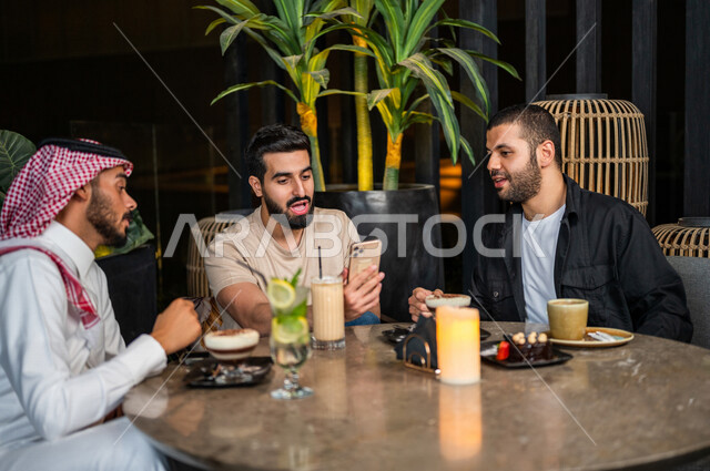 شباب عرب خليجيون سعوديون يجلسون في احد مقاهي المملكة العربية السعودية، استخدام جهاز الهاتف المحمول، تناول القهوة والمشروبات الباردة والحلى اللذيذة، أجواء راقية، أنشطة شبابية ترفيهية، الأجواء الشبابية في المقاهي السعودية